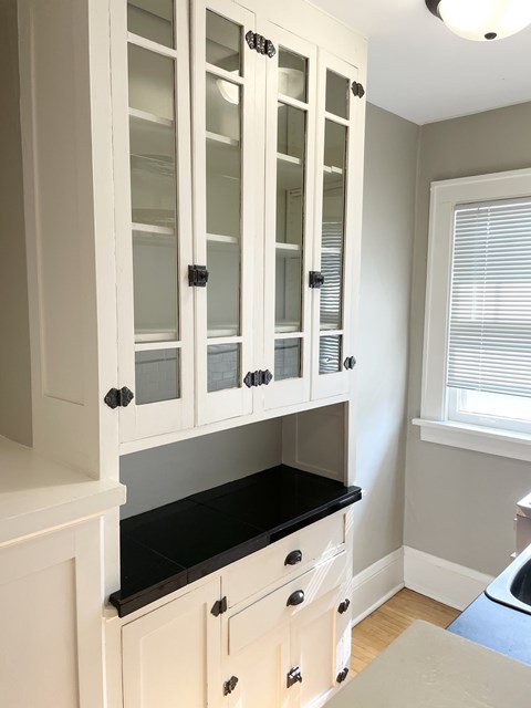 A kitchen with white cabinets and a black countertop.