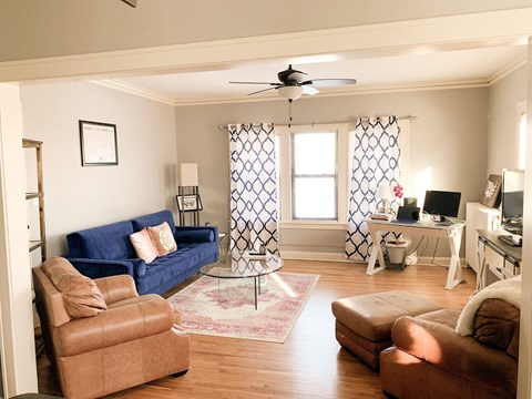 A living room with a blue couch and brown chairs.