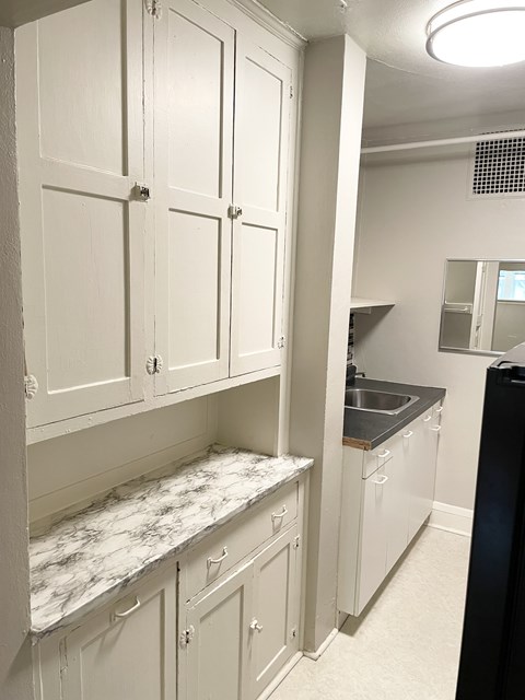A kitchen with white cabinets and a marble countertop.