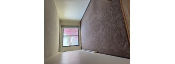 A room with a window and a brown wall.