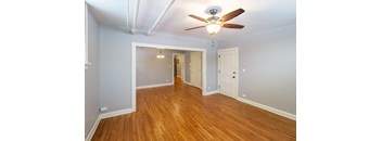 A room with a ceiling fan and wooden floors.