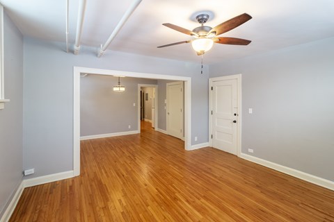 A room with a ceiling fan and wooden floors.