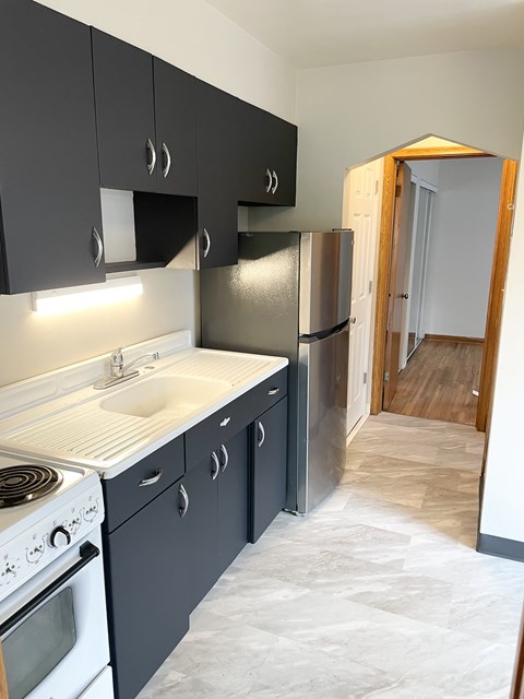 A kitchen with black cabinets and a white sink.
