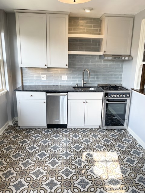 A kitchen with a patterned floor and white cabinets.
