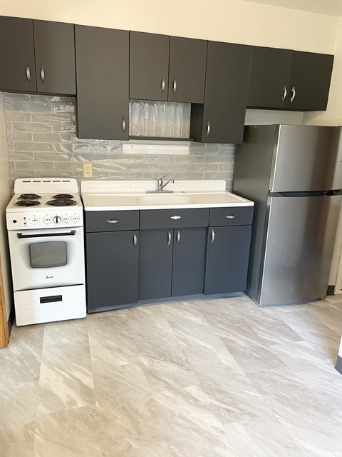 A kitchen with a white stove and a silver refrigerator.