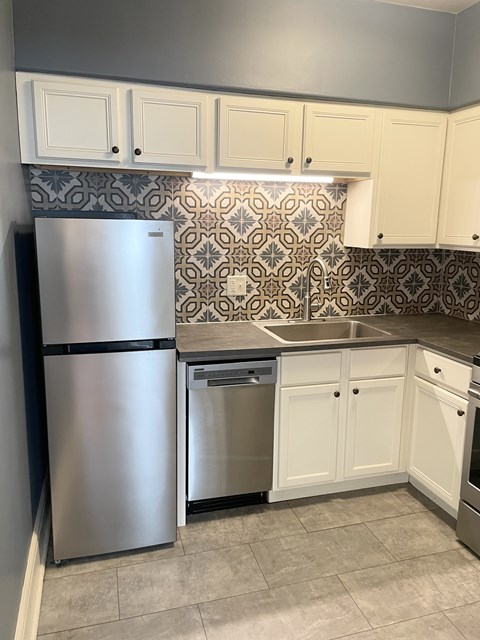 A kitchen with a stainless steel refrigerator and white cabinets.