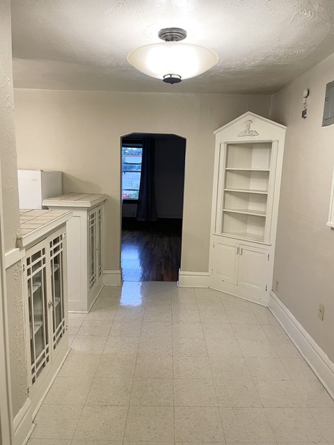 A kitchen with white cabinets and a black refrigerator.