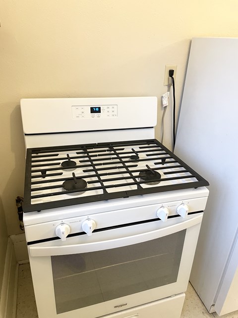 A white gas stove with four burners and two ovens.