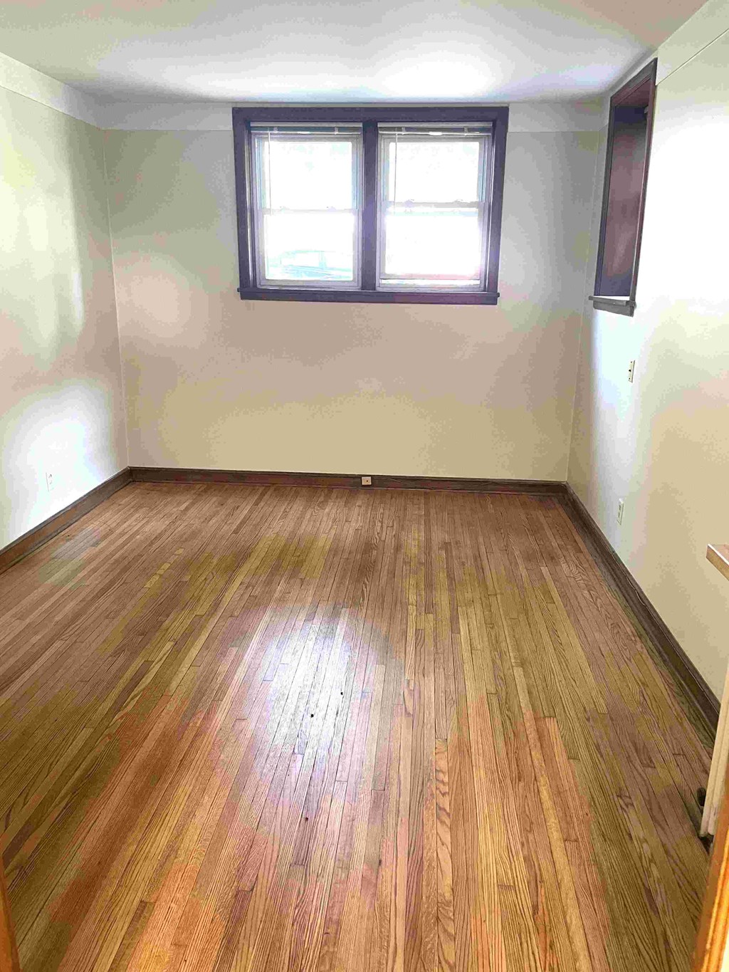 A room with wooden flooring and a window.
