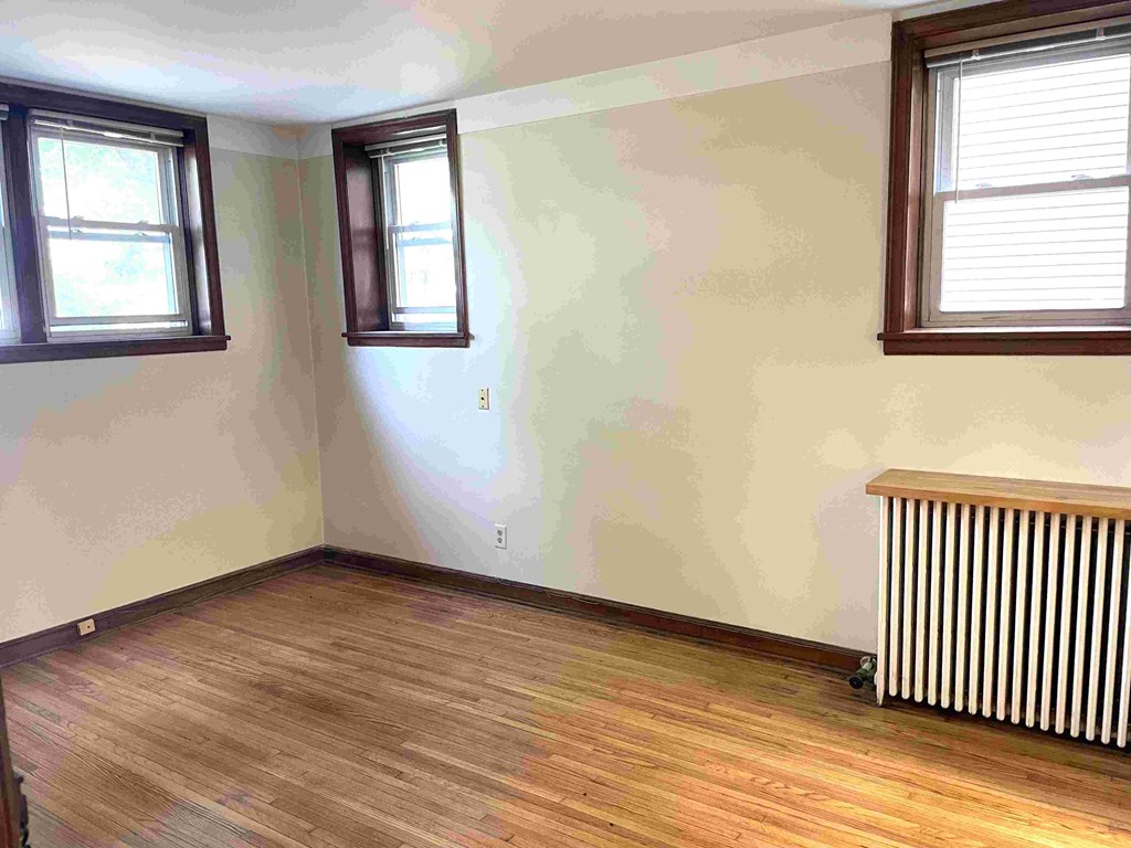 A room with wooden floors and two windows.