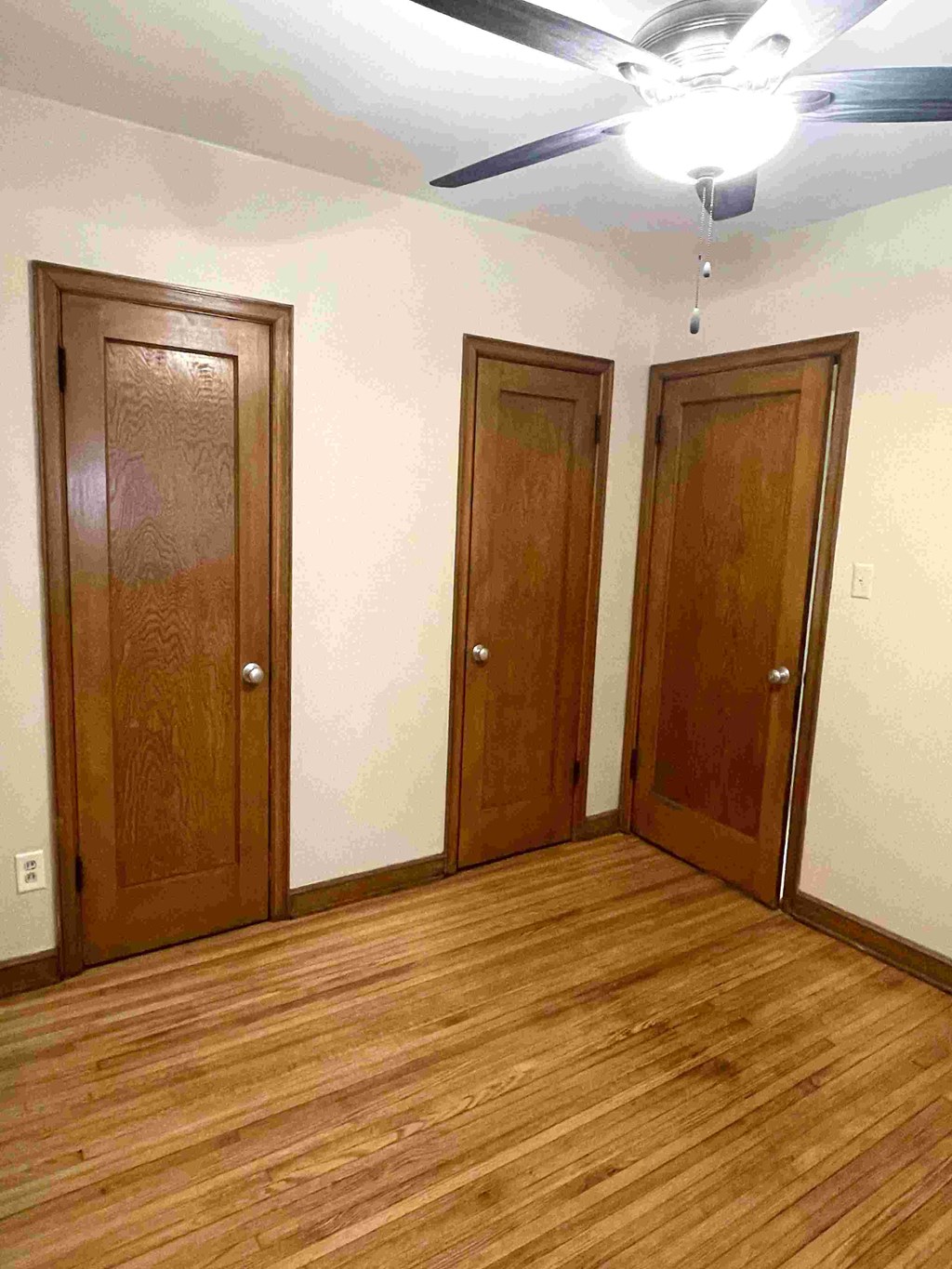A room with a ceiling fan and two doors.