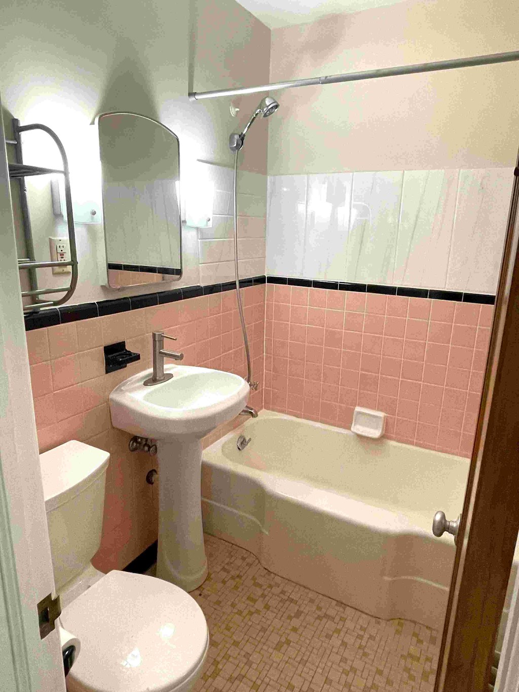 A bathroom with pink tiles and a white sink.