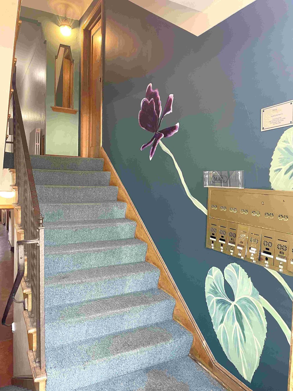 A staircase with a painting of a flower on the wall.