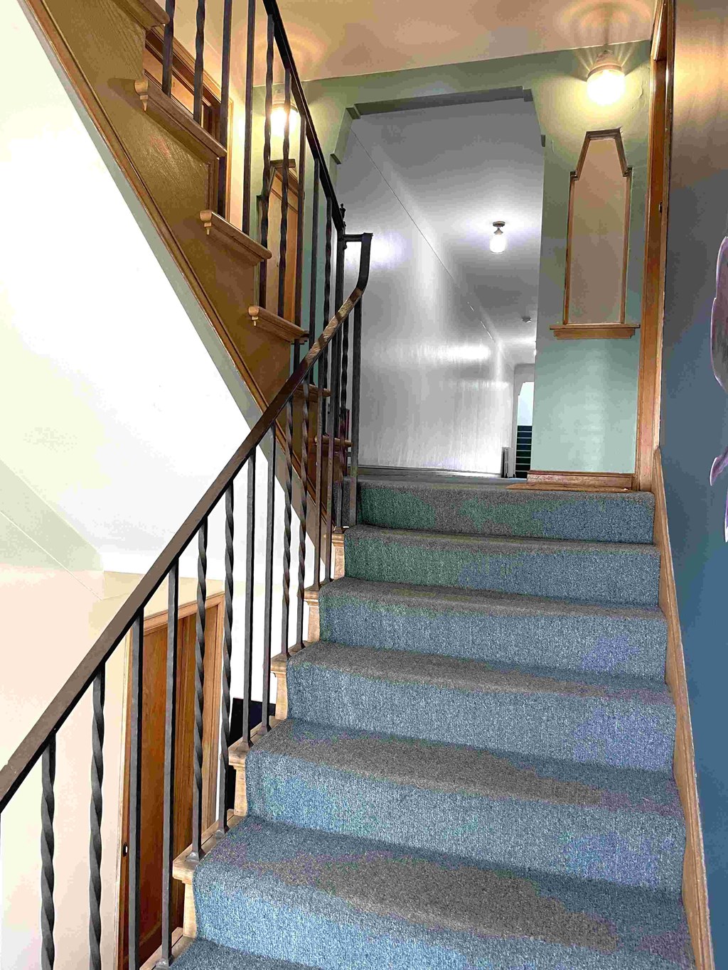 A staircase with a wooden handrail and a carpeted runner.