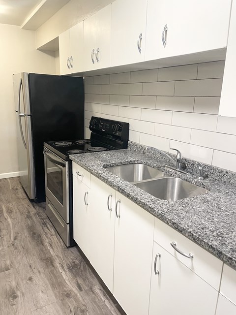 A kitchen with a black fridge and stove top oven.