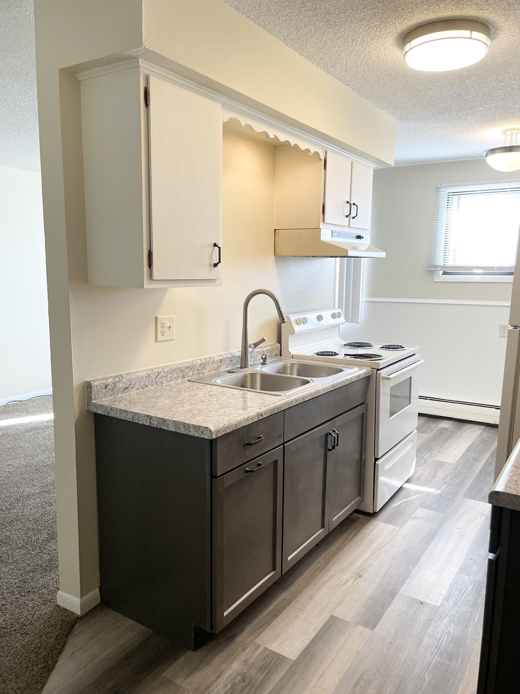 A kitchen with a sink, stove, and cabinets.