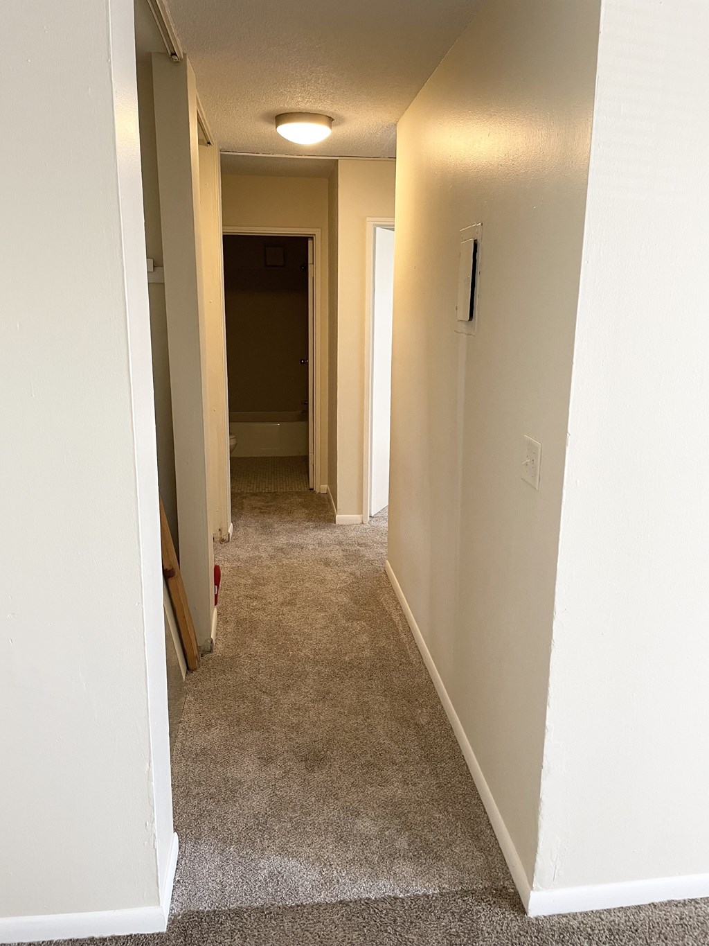 A long, narrow hallway with a carpeted floor and white walls.