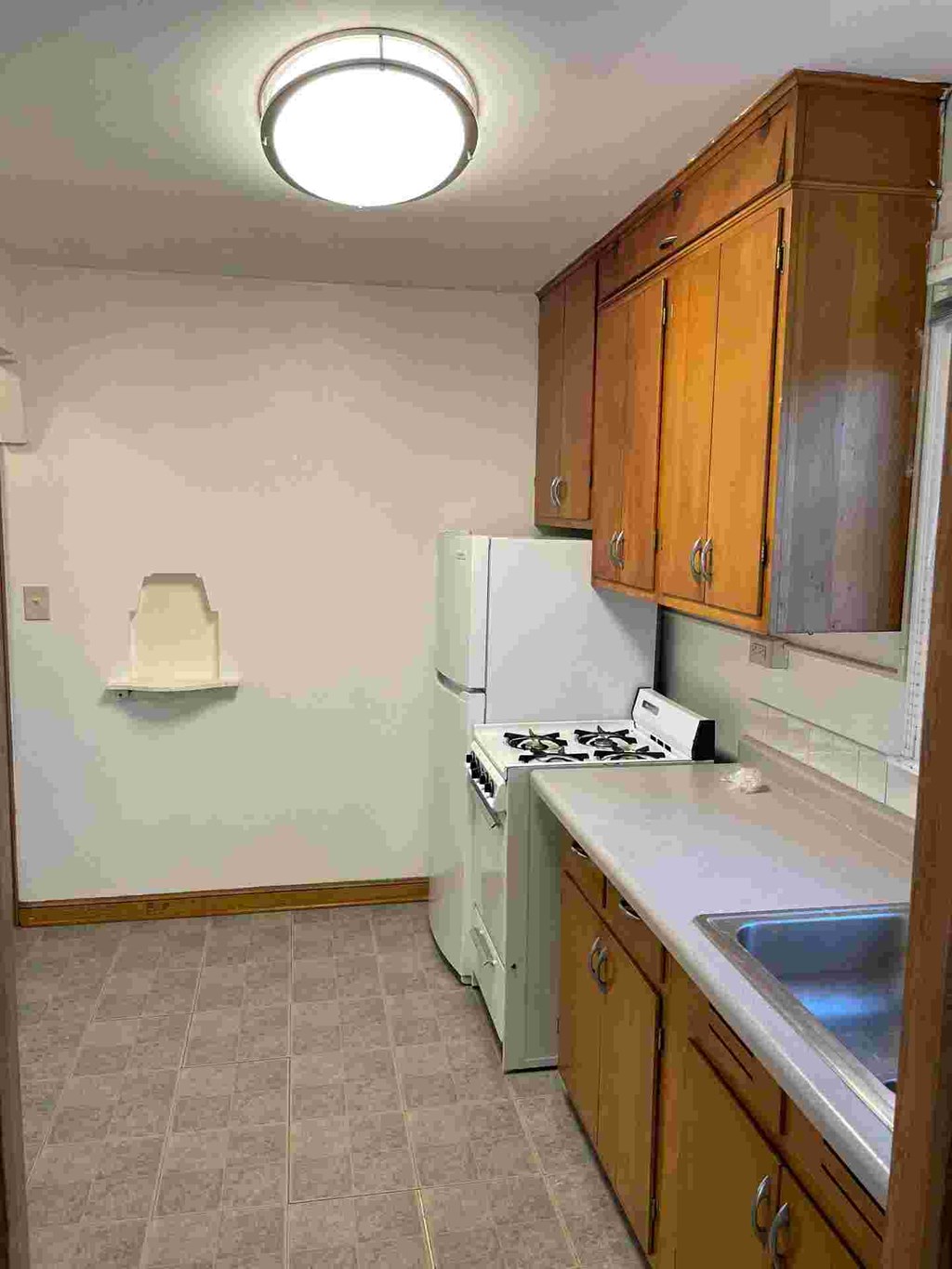 A kitchen with a white refrigerator, wooden cabinets, and a white stove top oven.