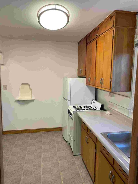 A kitchen with a white refrigerator, wooden cabinets, and a white stove top oven.