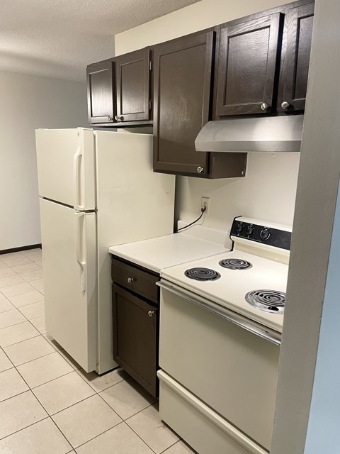 A white refrigerator and a white stove with a black dishwasher in a kitchen.