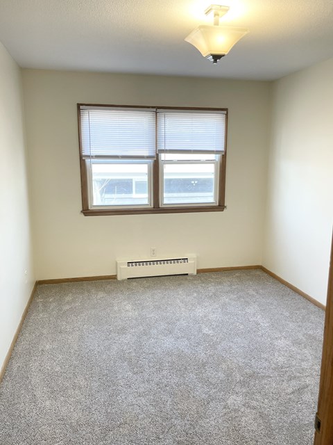 A room with a window and a heater on the floor.