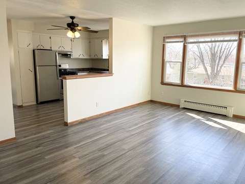 A kitchen with a refrigerator, cabinets, and a ceiling fan.