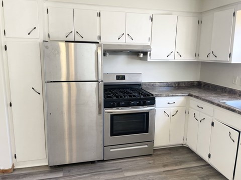 A kitchen with a stainless steel refrigerator, oven, and cabinets.
