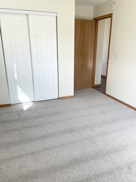A room with a carpeted floor and a white door.