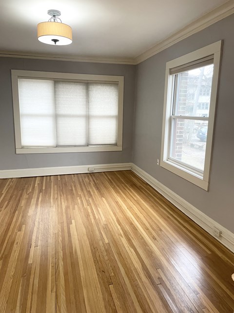 A room with wooden flooring and a window with blinds.