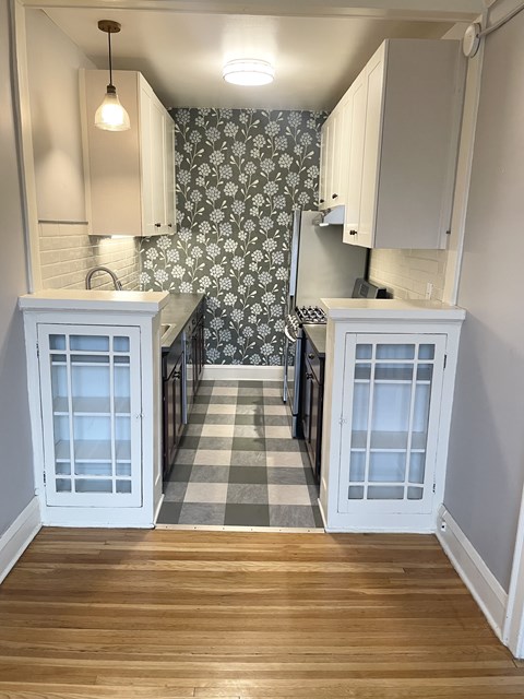A kitchen with white cabinets and a checkered floor.