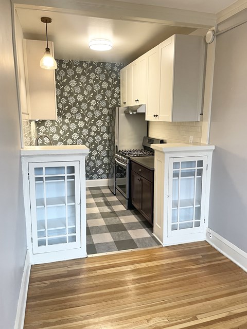 A kitchen with a checkered floor and white cabinets.