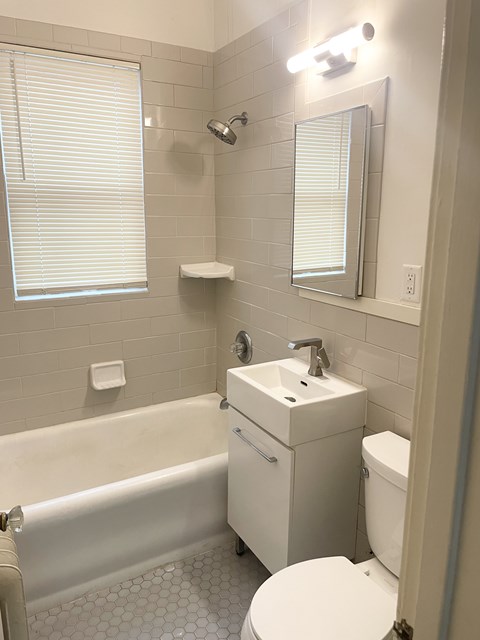 A white bathroom with a toilet, sink, and bathtub.