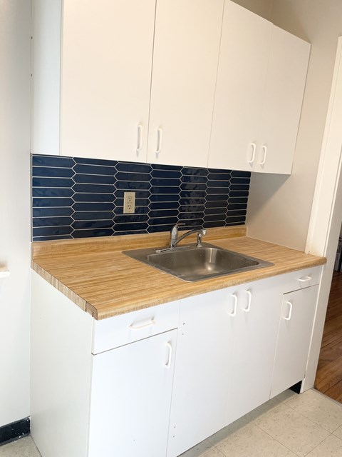 A kitchen with white cabinets and a wooden counter top.