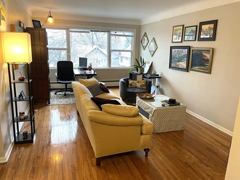 A living room with a couch, chair, and pictures on the wall.