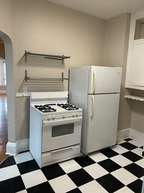 A black and white checkered floor in a kitchen with a stove and refrigerator.