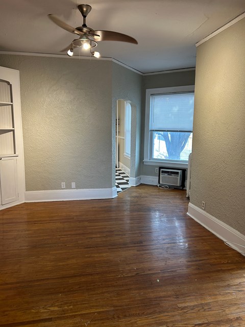 A room with a ceiling fan and wooden floors.