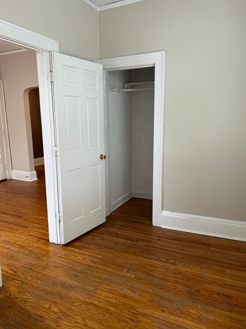 A white door is open to a room with wood flooring.