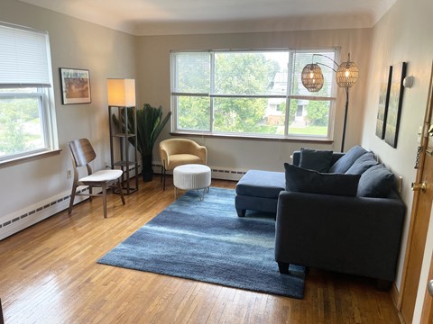 A living room with a grey couch, a chair, a table, and a rug.