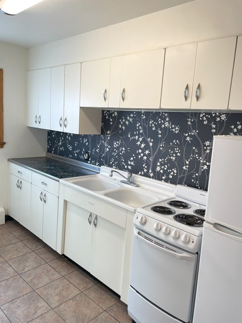 A kitchen with white cabinets and a black counter top.