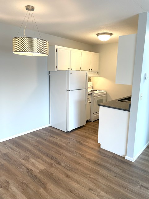 A kitchen with a white refrigerator and wooden floors.