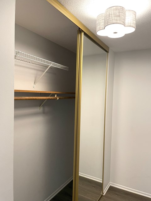 A white closet with a shelf and a light on.