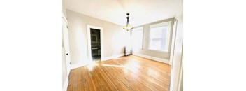 A room with wooden floors and a chandelier hanging from the ceiling.