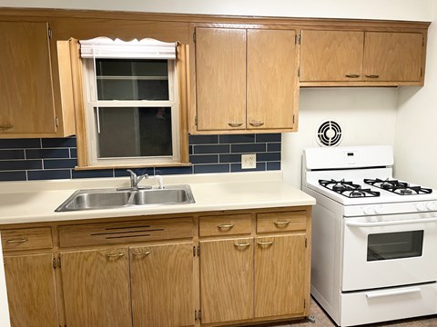 A kitchen with wooden cabinets and a white stove.