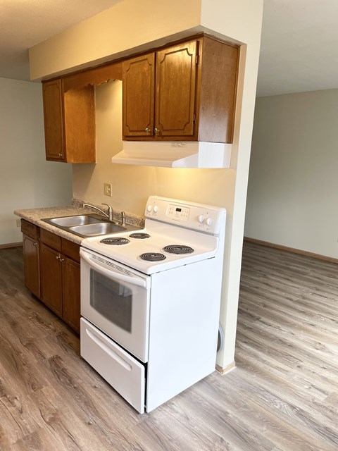 A white stove and oven in a kitchen with wooden cabinets.
