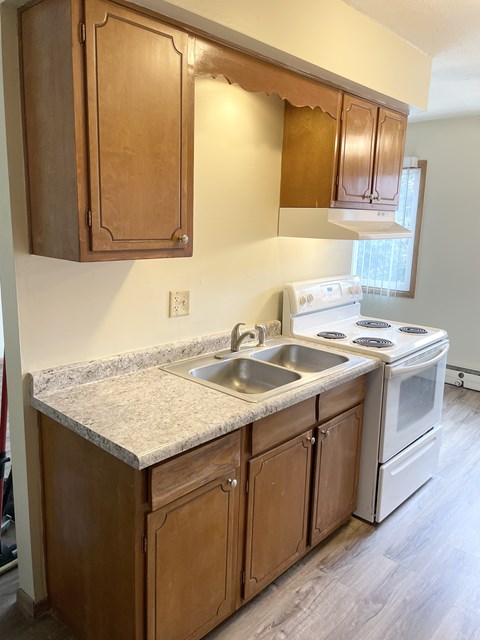 A kitchen with a white stove and wooden cabinets.