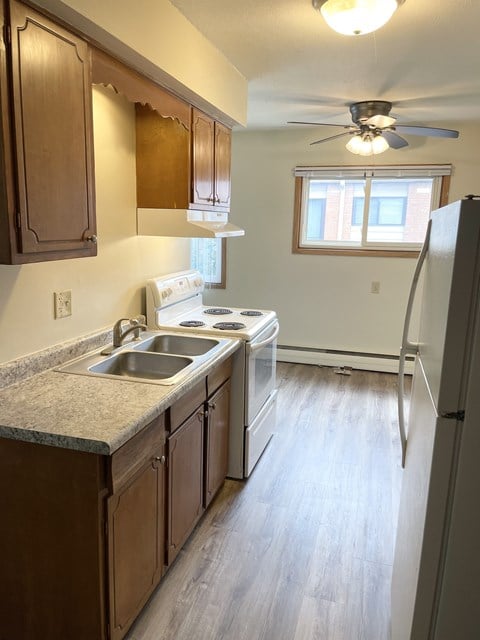 A kitchen with wooden cabinets and a white stove top oven.