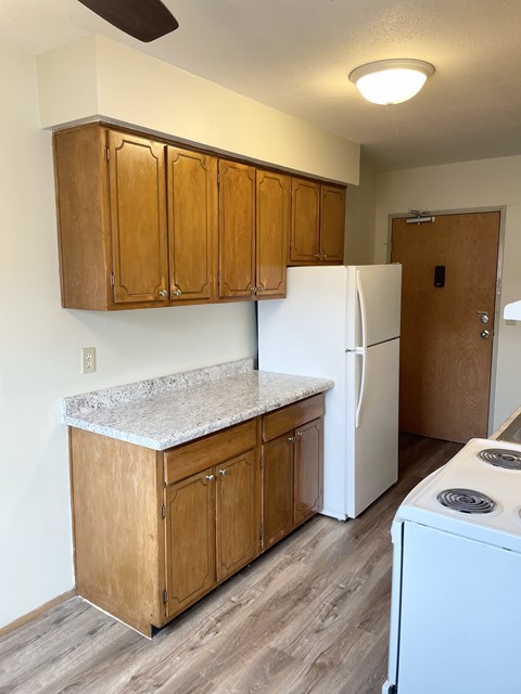 A kitchen with a white fridge and wooden cabinets.
