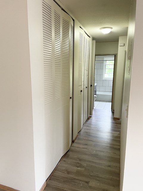 A long hallway with white walls and wood floors.