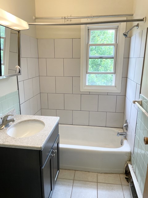 A white bathroom with a black vanity and a white tub.
