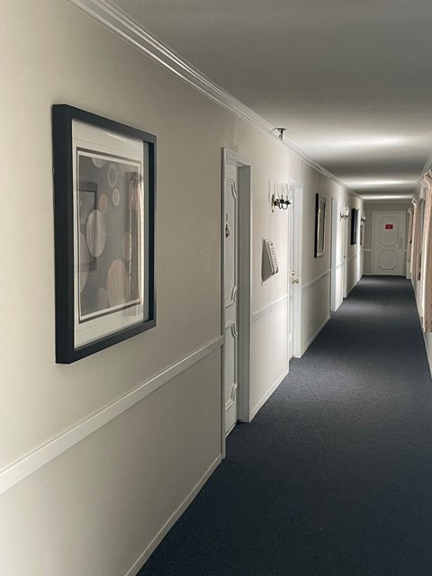 A long hallway with doors on both sides and pictures on the wall.